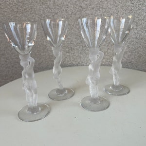 May include: Set of four clear glass shot glasses with frosted figures of women on the stems.