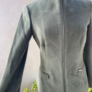 May include: A dark green zip-up jacket with a high collar and two zippered pockets on the sides.