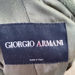 May include: A black label with white stitching and the text "Giorgio Armani" in white lettering. The label also has the text "Made in Italy" in white lettering.