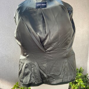 May include: A dark green blazer with a satin lining. The label on the inside reads "Giorgio Armani" in black text.