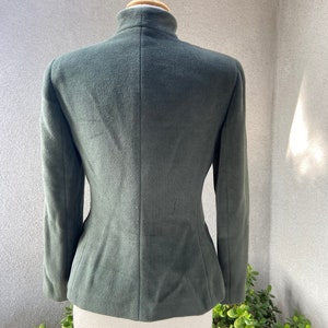 May include: A dark green, fitted, long-sleeved jacket with a high collar.