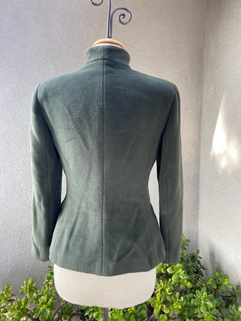 May include: A dark green, fitted, long-sleeved jacket with a high collar.