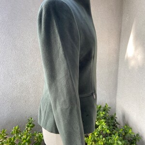 May include: A dark green, long-sleeved jacket with a high collar and a zipper closure. The jacket has a slim fit and is made of a soft, textured fabric.
