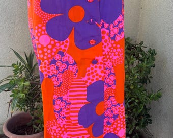 May include: A vibrant, vintage skirt featuring a bold floral pattern in orange, purple, and pink. The design includes large stylized flowers and polka dots. The skirt has a button closure and a fitted silhouette, perfect for a retro look.