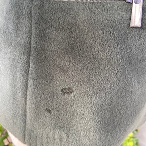 May include: A dark green jacket with a zipper closure. The jacket has a small hole in the fabric.