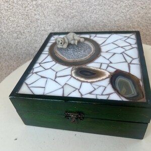 May include: A green wooden box with a mosaic tile lid. The lid features a white tile pattern, inlaid agate stones, and a small, light-colored dog figurine. The box has a metal clasp.