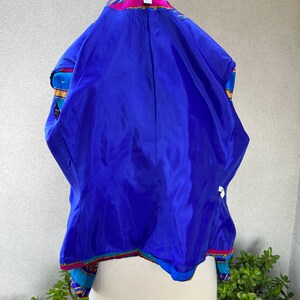 May include: A blue, pink, and gold patterned blazer with a blue satin lining. The blazer has a collar and a button closure. The label on the blazer reads "Bakeman".
