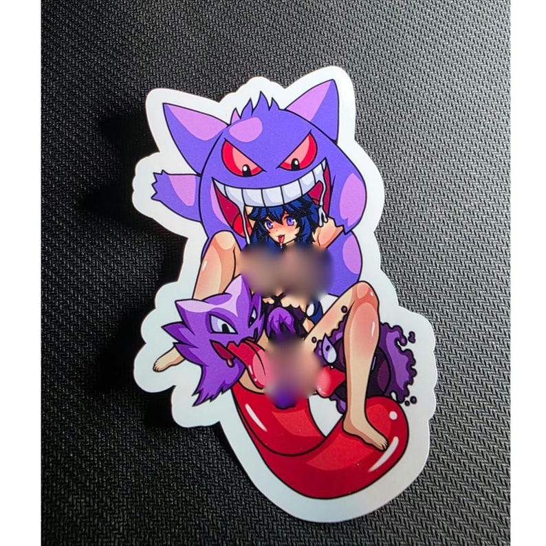 May include: A sticker featuring a purple cartoon character with a large grin and red eyes, with a woman in the middle. The sticker has a white border and is on a dark surface.
