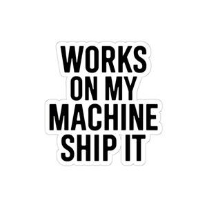 May include: A die-cut sticker featuring bold, black, sans-serif capital letters on a white background. The text reads: WORKS ON MY MACHINE SHIP IT. The sticker has a clean, contoured white border following the shape of the block-style text layout.