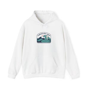Könnte beinhalten: Weißer Kapuzenpullover mit Fronttasche und Kordelzug. Das Design auf der Vorderseite zeigt ein Kreuz und den Text "I left it in the water" über einer stilisierten Ozeanszene in Blau- und Türkistönen.