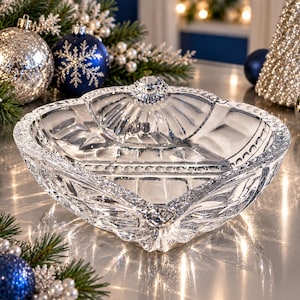 May include: A clear, pressed glass bowl with a square shape and rounded corners. The bowl features a decorative scalloped rim and a textured, geometric pattern on the exterior sides, with a smooth, reflective interior surface.