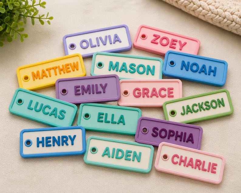 May include: Colorful name tags in various pastel colors, each with a different name in bold, raised letters. The tags are rectangular with rounded corners and a small hole on one side. Names include Olivia, Zoey, Matthew, Lucas, Mason, Emily, Grace, Noah, Jackson, Ella, Sophia, Henry, Aiden, and Charlie.