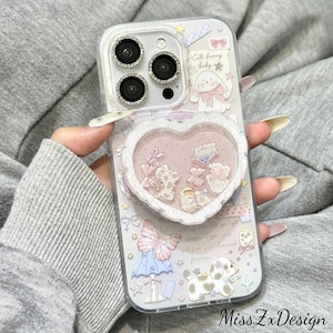 May include: A clear phone case featuring a heart-shaped shaker element filled with small charms. The case is decorated with pastel illustrations of a bunny, a puppy, a butterfly, and stars. The text "Cute bunny baby" is printed on the back.