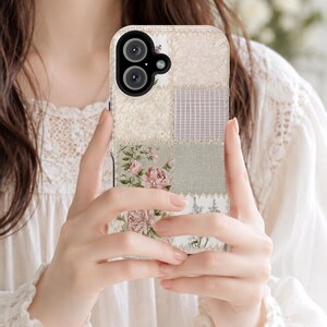 Puede incluir: Una funda para smartphone con un diseño de patchwork que presenta varias texturas y patrones. La superficie muestra cuadrados de encaje crema, cuadros vichy morados claros, tela beige lisa y estampados florales con rosas y lavanda.
