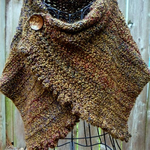 May include: A brown, gold and purple crocheted shawl with a wooden button. The shawl is draped over a black metal dress form.