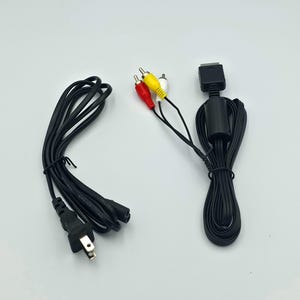 May include: Black AV cable with red, white, and yellow RCA connectors. The cable has a black power cord with a two-prong plug. The cable is for a gaming console.