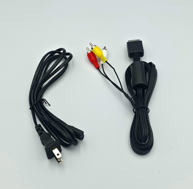 May include: Black AV cable with red, white, and yellow RCA connectors. The cable has a black power cord with a two-prong plug. The cable is for a gaming console.