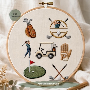 May include: Embroidered golf-themed design on cream fabric within a wooden hoop. The design features a golf bag, golfer, golf cart, golf glove, golf ball, and crossed golf clubs. The text "Asha Embroidery Studio" is visible.