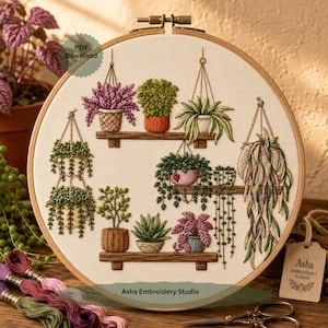 May include: Embroidered hoop art featuring a collection of potted plants on wooden shelves. The plants include hanging varieties and succulents, with detailed stitching in shades of green, pink, and brown. The text "PDF Download" and "Asha Embroidery Studio" are visible.