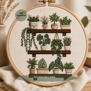 May include: Embroidery hoop art featuring a detailed depiction of various potted plants on wooden shelves. The design includes a variety of green foliage and flowers, all meticulously stitched. The text "PDF Download" and "Asha Embroidery Studio" are visible.