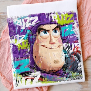 May include: A rectangular canvas print featuring a stylized portrait of the character Buzz Lightyear. The artwork incorporates vibrant graffiti-style splashes of purple, lime green, and cyan paint, with the repeated text BUZZ layered in the background.