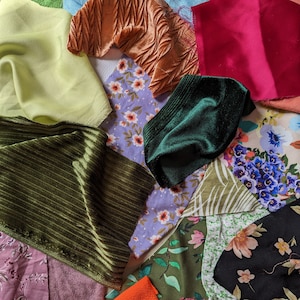 May include: A collection of fabric swatches in various colours and patterns, including green, orange, pink, black, and brown. The fabrics are arranged in a random pattern, creating a visually interesting display.