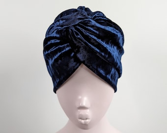 May include: A navy blue velvet turban. The turban is made of soft, luxurious fabric and has a classic, elegant design.