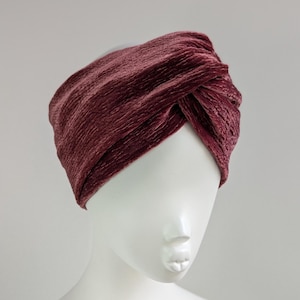 Op de afbeelding: Een bordeauxrode fluwelen turban hoofdband. De hoofdband is gemaakt van een zachte, rekbare stof en is ontworpen om als turban te worden gedragen.