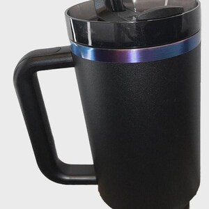 May include: Black insulated travel mug with a handle and a clear straw. The mug has a black lid and a blue and purple iridescent band around the middle. The mug is designed to keep beverages hot or cold.
