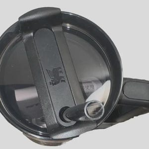 May include: A black Stanley tumbler lid with a flip-top closure and a built-in straw. The lid features the Stanley logo and is designed for easy use and spill resistance. The image is taken from a top-down perspective.