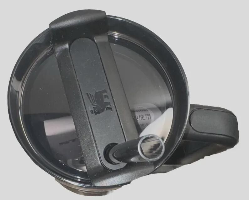 May include: A black Stanley tumbler lid with a flip-top closure and a built-in straw. The lid features the Stanley logo and is designed for easy use and spill resistance. The image is taken from a top-down perspective.