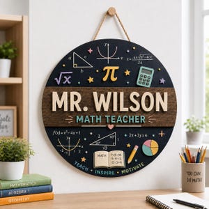 Peut inclure: Un panneau mural circulaire en bois noir portant le texte MR. WILSON et MATH TEACHER. Le panneau est décoré de symboles mathématiques 3D colorés, d'une calculatrice, d'un livre, d'un crayon et d'un graphique circulaire. Il est suspendu par une corde beige.