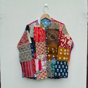 May include: A long-sleeved jacket constructed from a patchwork of various cotton fabrics featuring diverse patterns including floral, geometric, and polka dot prints in red, blue, brown, and yellow. The jacket has a mandarin collar and buttons.