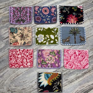 May include: Ten rectangular fabric pouches with zippered closures, each featuring distinct floral, botanical, or animal patterns in various colors including pink, green, blue, black, and red, all arranged in a grid on a light gray surface.