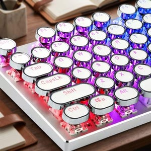 May include: A retro-style mechanical keyboard with round, silver-rimmed keys. The keys are white with black lettering and feature a variety of symbols and functions. The keyboard has a silver base and is illuminated with purple and red lights.