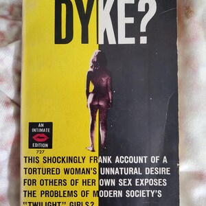 May include: A vintage paperback book titled Was she a DYKE? with a split yellow and black cover. The front features a silhouette of a person, the text AN INTIMATE EDITION 727, and a blurb describing the account of a woman's desire for her own sex.