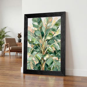 May include: A framed artwork featuring a vibrant painting of a banana plant. The artwork showcases broad green leaves with hints of yellow and peach, set against a white background. The painting is enclosed in a black wooden frame, adding a touch of elegance.