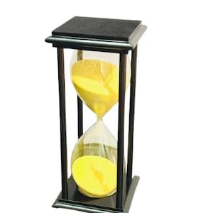 May include: An hourglass with a black wooden frame and a clear glass bulb filled with yellow sand. The hourglass is a decorative item, likely used for timing or as a visual display. The sand is flowing from the top bulb to the bottom.