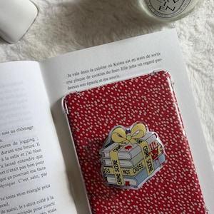 Op de afbeelding: Een rood en wit gestippelde telefoonhoes met een doorzichtige overlay, met een stapel boeken met een gele strik en de woorden "Crime Scene" en "Not Cross."