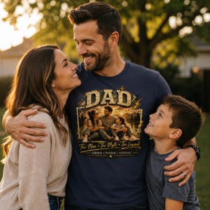 May include: Navy blue t-shirt with the word "DAD" in a distressed gold font. The shirt features a family portrait design with the text "The Man * The Myth * The Legend" and the names EMMA * NOAH * OLIVIA.