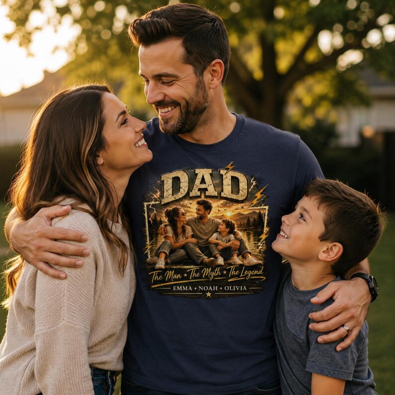 May include: Navy blue t-shirt with the word "DAD" in a distressed gold font. The shirt features a family portrait design with the text "The Man * The Myth * The Legend" and the names EMMA * NOAH * OLIVIA.