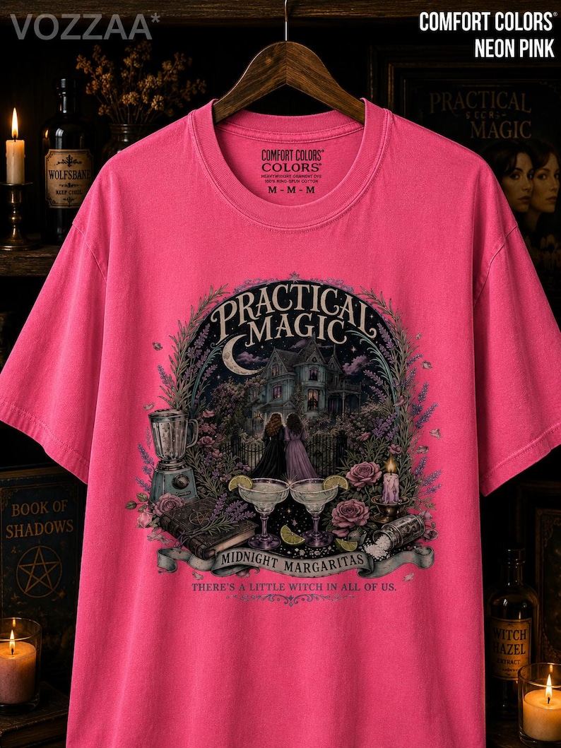 May include: A neon pink short-sleeve t-shirt featuring a graphic print of a house, two figures, a blender, and two margaritas. The text reads Practical Magic, Midnight Margaritas, and There's a Little Witch in All of Us. The shirt has a crew neckline.