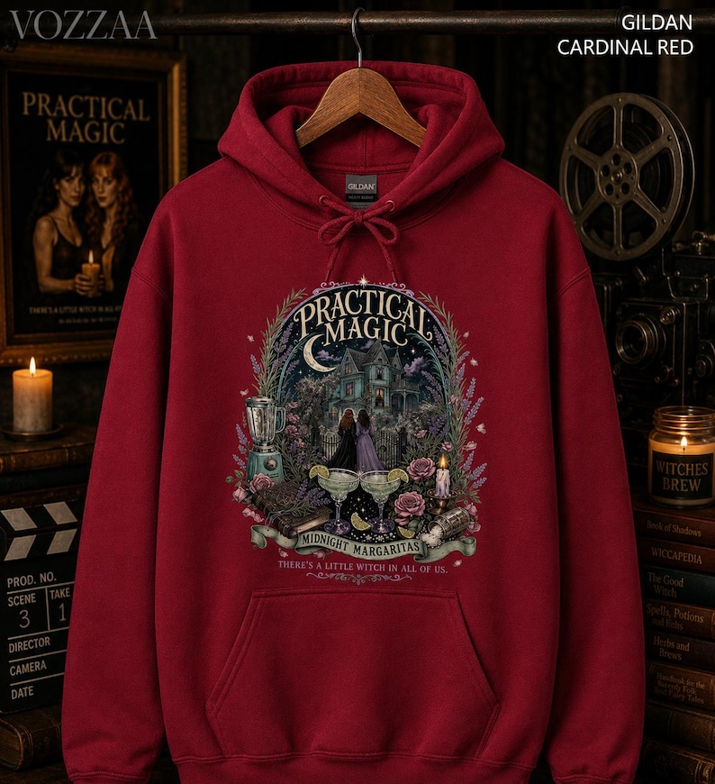 Op de afbeelding: Een kardinaalrode hoodie met een grafische print met de tekst Practical Magic, Midnight Margaritas en There's a little witch in all of us. Het ontwerp bevat een huis, twee figuren, een blender en twee margaritaglazen.