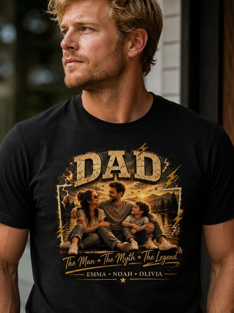 May include: Black t-shirt featuring a graphic with the word "DAD" in a distressed gold font. The graphic includes a family portrait with the text "The Man * The Myth * The Legend" and the names Emma, Noah, and Olivia.