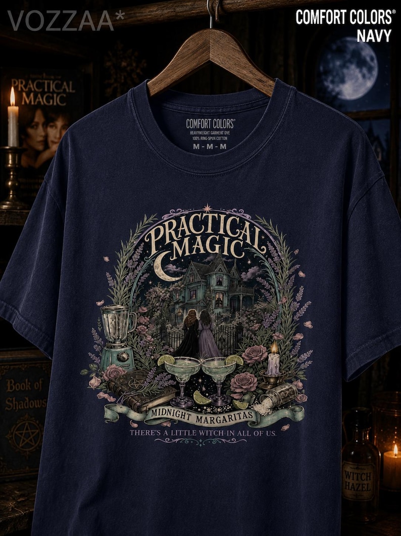 May include: A navy blue t-shirt featuring a graphic print with the text "Practical Magic" and "Midnight Margaritas" along with "There's a little witch in all of us." The design includes a house, two people, a blender, margaritas, and flowers.