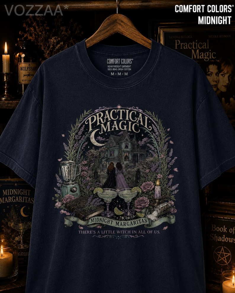May include: A dark navy blue t-shirt featuring a graphic print of a Victorian house, two figures, a blender, two margaritas, and roses. The text reads Practical Magic, Midnight Margaritas, and There's a little witch in all of us. The shirt is size M.