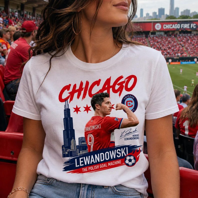 May include: A white t-shirt featuring a graphic of Robert Lewandowski flexing his arm, the Chicago skyline, and the text "CHICAGO", "LEWANDOWSKI", "THE POLISH GOAL MACHINE", and a signature. The design includes red stars, a soccer ball, and a logo.