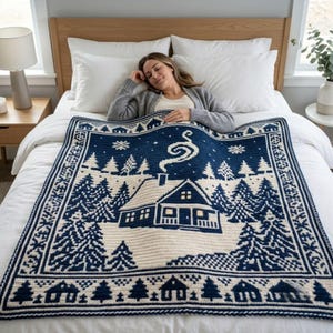 Könnte beinhalten: Eine marineblaue und cremefarbene Strickdecke mit einem Winterlandschaftsmuster, das eine zentrale Hütte, Tannenbäume und wirbelnden Kaminrauch zeigt. Der Rand ist mit einem sich wiederholenden Motiv aus kleinen Häusern und Tannen verziert.