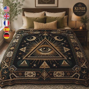 May include: A black woven blanket featuring a large central eye inside a triangle, surrounded by sunburst rays, stars, and crescent moons. The design includes geometric borders with intricate patterns in gold, cream, and dark green tones.