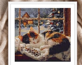 Puede incluir: Un kit de pintura de diamantes cuadrado que muestra un gato calicó acurrucado sobre un paño de encaje blanco. El gato está frente a una ventana con vistas a un paisaje invernal nevado, una casa iluminada y un árbol de Navidad decorado.